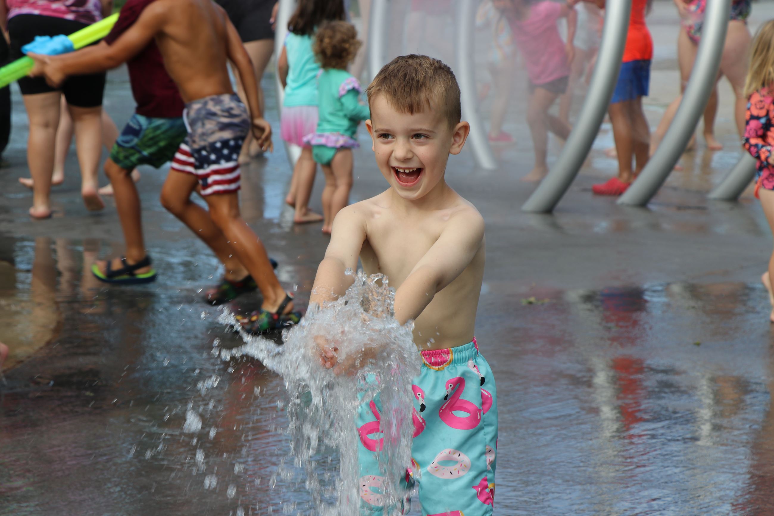 Little boy getting sprayed with water at the Lions Park splash pad.