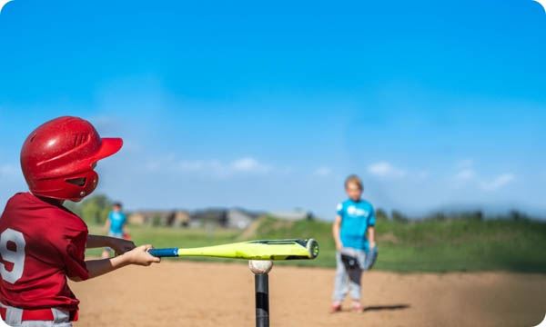 Youth Batter Hitting a Tee Ball into an Open Field at Game