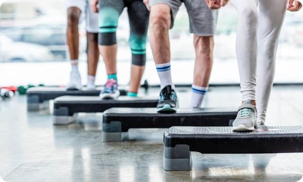 People Doing Exercise on Step Platforms at Gym