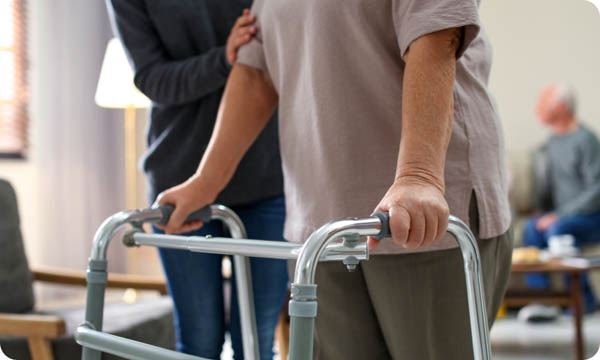 Care Worker Helping to Elderly Woman with Walker